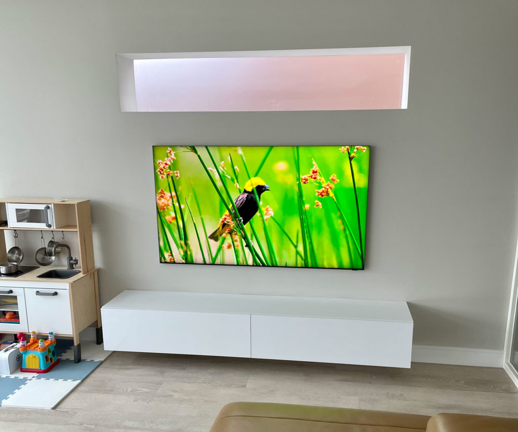 TV mounted with hidden cabling in the wall and the devices are in the floating cupboard below